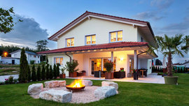 Haus Lehman beeindruckt mit der hellen Feuerstelle aus Naturstein, die einen mediterranen Charme besitzt. (Foto: BAUMEISTER-HAUS)