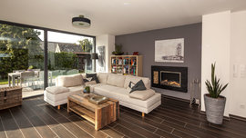 Um Platz im Wohnzimmer zu schaffen, kann der Kamin im Eigenheim auch in die Wand eingebaut werden, genau wie die elegante Lösung in Haus Vettel. (Foto: BAUMEISTER-HAUS)